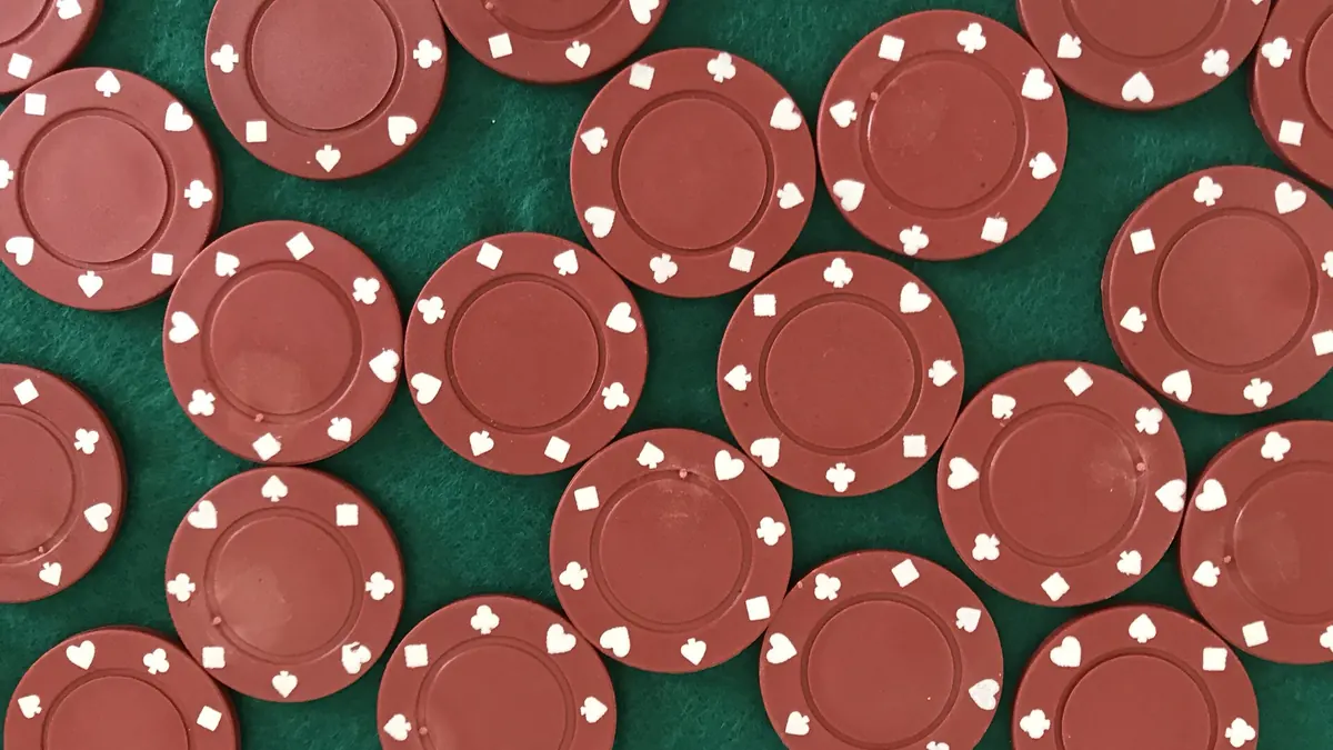 Red chips with card-suit symbols on green felt — Elon Casino